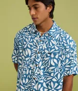 Camisa de manga corta color azul con estampa floral abstracta en color blanco, de corte relaxed, con cuello solapa, cierre frontal de botones y un bolsillo aplicado en el pecho.