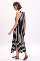 Vestido midi de punto sin mangas, con diseño a rayas verticales en color negro y blanco, escote redondo y tajo lateral en el bajo.