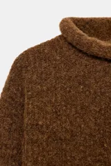 Jersey de punto con textura, cuello subido y manga larga, de corte recto y diseño clásico.