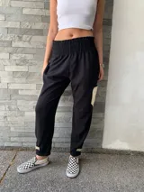 Pantalón negro de lana fina con detalles de cuero en los laterales. Presenta cintura elastizada y corte holgado.