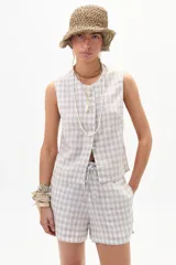 Top sin mangas color beige con estampado a cuadros blancos, con botones frontales.