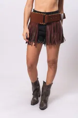 Falda de cuero sintético color marrón con flecos largos y cinto ancho con hebilla cuadrada.