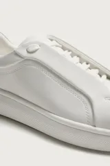 Zapatilla urbana de diseño minimalista en color blanco, con cordones ocultos y suela de plataforma a tono.