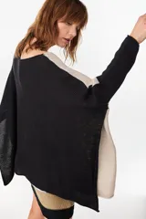 Poncho oversize de tejido de punto con hilos de lurex, color negro, con escote redondo y aberturas laterales en las mangas.