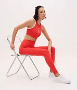 Pantalón legging deportivo de tiro alto, confeccionado en microfibra elástica de color rojo. Presenta un diseño ajustado al cuerpo con costuras reforzadas que brindan soporte y libertad de movimiento.
