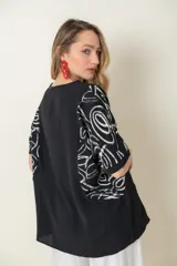 Blusa negra de mangas cortas con estampado abstracto en blanco y corte holgado. 