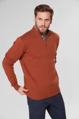 Buzo de lana color terracota con cuello alto y cierre frontal parcial. Presenta puños y ruedo acanalados, con detalle de logo bordado en el pecho y tirador de cierre en cuero.