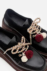 Zapato tipo mocasín de plataforma color bordó, confeccionado en una combinación de cuero liso y gamuza. Presenta cordones bicolores con detalle de borlas decorativas en el empeine.