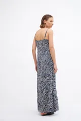 Maxi vestido de tirantes finos con estampado abstracto de líneas onduladas en tonos azul, negro y crema. Presenta un corte fluido y holgado con un ligero vuelo en el ruedo.