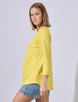 Blusa amarilla de tejido acanalado con cuello redondo, escote en V y aplique metálico. Manga ¾.