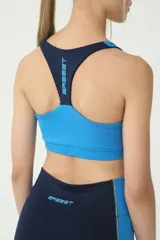 Top deportivo azul y celeste con costuras en verde, espalda cruzada y logo retro de Basset.