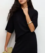 Blusa de manga corta amplia y sisas desplazadas, confeccionada en punto leve de viscosa y poliamida, con cuello redondo ligeramente alto.