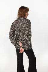 Camisa de lino italiano con estampado a rayas verticales irregulares, de corte holgado, cuello clásico, mangas abullonadas y cierre frontal con botones.