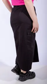 Falda midi color negro, de corte recto, con bolsillos cargo laterales y abertura frontal.