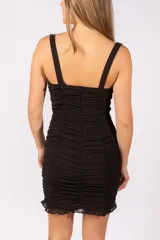 Vestido corto negro con diseño fruncido en toda la prenda, escote con cordones ajustables y breteles anchos. Presenta un ruedo con detalle de volado sutil.