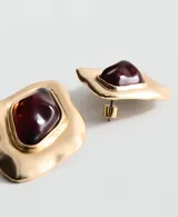 Aros de diseño irregular con estructura de metal dorado y aplique central de resina en tono rojizo. Cierre metálico a presión.