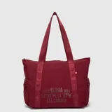 Bolso tipo tote bag de la marca Bubba, modelo Mila, en color bordó con doble asa de hombro de cinta estampada y bolsillos laterales con cierre. Presenta la inscripción gráfica frontal de la marca y coordenadas.
