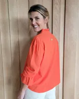 Blusa de algodón con cuello mao y volados, mangas largas con puños elásticos y corte holgado.