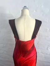 Vestido largo de microtul con estampado abstracto en tonos rojos y naranjas, con escote drapeado y tirantes finos.