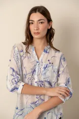 Camisa blanca con estampado de hojas y flores en color azul, de corte clásico, con cuello mao y mangas 3/4 con botón para sujetar.
