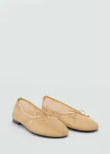 Zapato tipo bailarina de tejido de malla en color dorado, con detalle de lazo decorativo en la puntera y ribete metalizado.