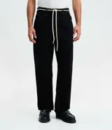 Pantalón masculino de corte baggy, confeccionado en sarga de algodón. Presenta un diseño holgado con costuras en contraste, cierre tradicional y cordón ajustable en la cintura.