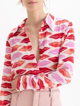 Camisa de seda con estampado de labios en tonos rojos y rosas. Presenta cuello clásico, cierre frontal con botones ocultos y mangas largas con puños abotonados.