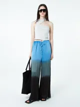 Pantalón palazzo celeste con degradé a gris y negro, de tiro alto con cintura elastizada y cordón ajustable.