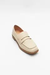 Mocasín de cuero sintético negro con punta cuadrada, detalle de costuras visibles en la capellada y taco bajo.