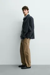 Parka de corte relajado confeccionada en mezcla de algodón color marrón. Presenta cuello solapa, cierre frontal con cremallera oculta y alamares metálicos, bolsillos de plastrón con solapa en la cadera y bolsillo de vivo en el pecho.