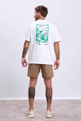 Remera blanca de manga corta con un pequeño estampado verde en el pecho que simula una caja abierta con un objeto dentro.