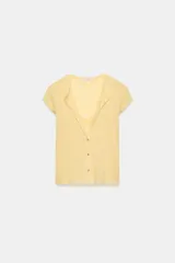 Top de manga corta color amarillo claro con escote redondo y cierre frontal de botones, con diseño que incluye un falso top interior con detalle de lazo en el pecho.