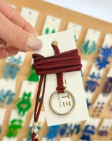 Gargantilla tipo choker con cordón de gamuza color bordó, dije circular plateado y cuentas plateadas.