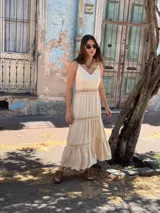 Vestido largo color beige, con tirantes finos, escote en V y detalles de inserciones de encaje broderie en la cintura y los volados de la falda.