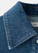 Blusa de algodón estilo denim, con diseño oversize, cuello camisero, mangas cortas, dos bolsillos de parche en el pecho y cierre frontal de botones.