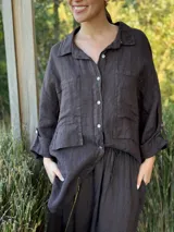 Camisa negra de manga larga con cuello clásico y cierre frontal con botones.