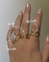 Set de tres anillos dorados: uno con forma de corazón, otro con una pieza rectangular y otro con una perla irregular.