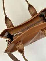 Cartera marrón de cuero genuino con doble asa corta y correa bandolera estampada con la frase "Chabas, soy real, no perfecta".