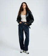 Pantalón baggy de jeans color azul oscuro, con tiro mediano, corte holgado y diseño de cinco bolsillos. Cuenta con cierre de cremallera y botón, y trabillas para cinturón.