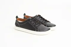 Zapatillas de cuero blanco con diseño minimalista, cordones al tono y suela de goma color suela con costura vista.