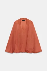 Top de punto color naranja con cuello polo, escote en V y mangas largas amplias con bajo abullonado.