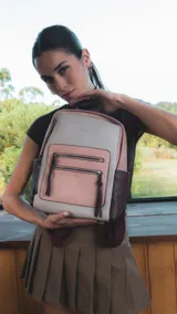 Mochila combinada en tonos beige, rosa y bordó, con apertura superior y dos bolsillos frontales con cierre metálico. Incluye bolsillos laterales y tres bolsillos internos. Tiene correa larga regulable y correas de espalda regulables.