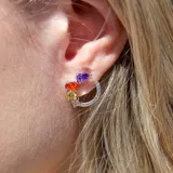 Par de aros tipo argolla plateados con cristales de colores engarzados.