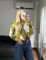 Sweater de tejido de punto con diseño de rombos en tonos verde oliva, verde oscuro y blanco. Presenta cuello redondo, mangas largas con puños acanalados y un corte holgado.