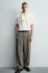 Pantalón de corte relajado con diseño de cuadros, confeccionado en tejido con lana. Presenta cintura con pliegues frontales, bolsillos laterales y bolsillos traseros de vivo, con cierre frontal de cremallera y gancho metálico oculto.