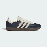 Zapatillas Adidas Samba OG con exterior de cuero azul marino y detalles en gamuza beige. Presentan las icónicas tres tiras laterales, suela de goma color marrón y el nombre del modelo en letras doradas.