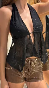 Top negro de tul transparente con cuello halter y diseño fluido, adornado con bordados florales y lentejuelas.