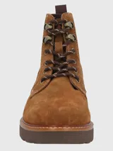 Bota acordonada de gamuza color marrón, con suela de plataforma dentada y paneles laterales elásticos. Presenta ojales metálicos y cordones bicolor.