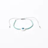 Pulsera elástica con cuentas celestes y doradas, y dije central redondo con diseño de ojo turco.