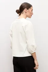 Remera blanca con mangas abullonadas y puños elásticos, de corte recto y escote redondo.